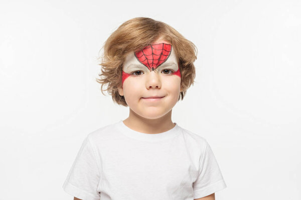 cute boy with superhero mask painted on face smiling at camera isolated on white