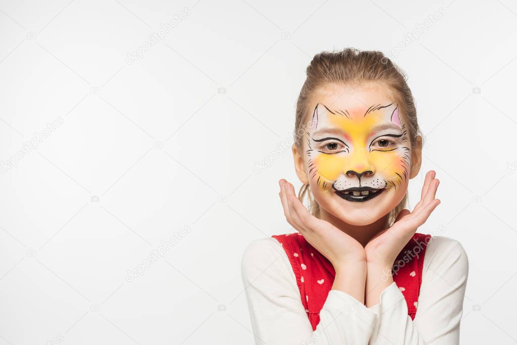 cute kid with tiger muzzle painting on face holding hands near face while looking at camera isolated on white