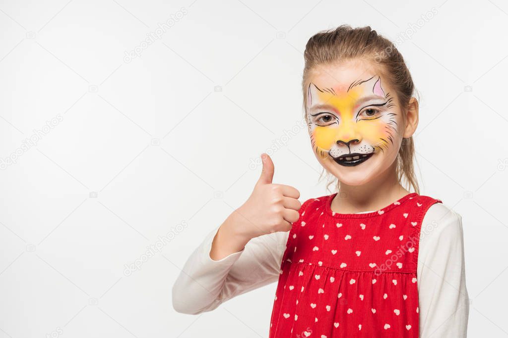 smiling child with tiger muzzle painting on face showing thumb up isolated on white