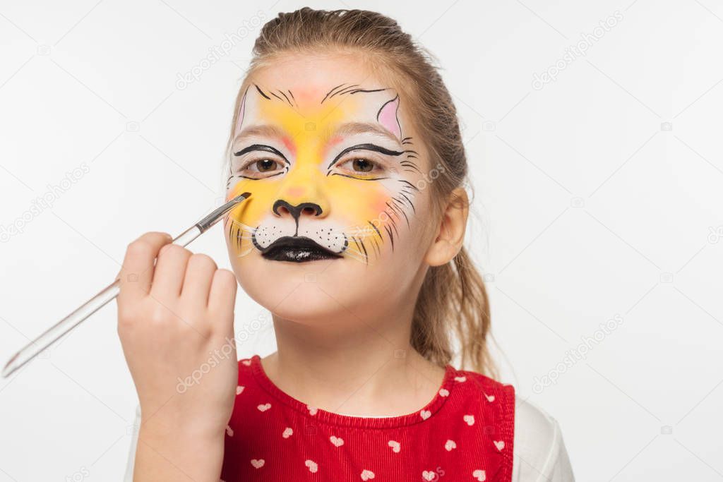cute kid with tiger muzzle painting on face holding paintbrush isolated on white
