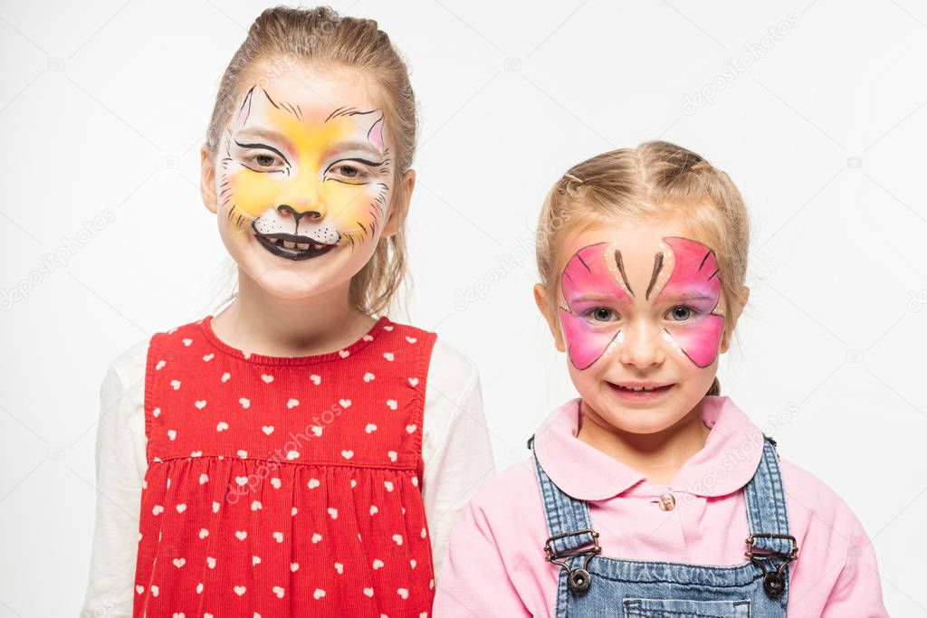 cute friends with cat muzzle and butterfly paintings on faces smiling at camera isolated on white