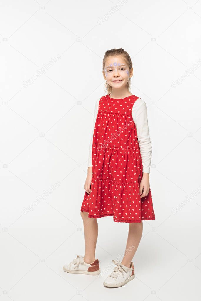 full length view of adorable child with floral painting on face standing on white background