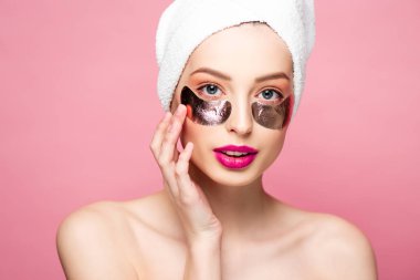 beautiful young woman in towel and eye patches isolated on pink 