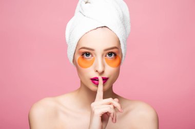 pretty naked girl with eye patches showing hush sign isolated on pink 