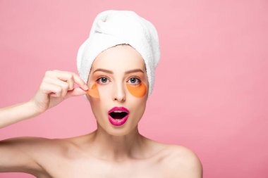 surprised and naked girl touching eye patch and looking at camera isolated on pink 