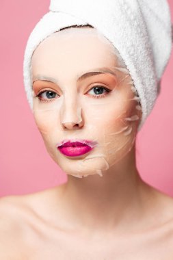 young naked woman in moisturizing face mask looking at camera isolated on pink 