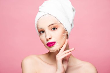 naked woman in moisturizing mask touching face isolated on pink 