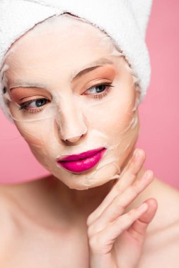 naked girl in moisturizing face mask looking away isolated on pink 