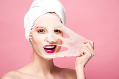 naked young woman touching face mask isolated on pink 