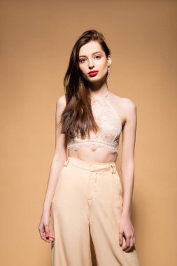 pretty young woman standing and looking at camera on beige 