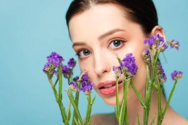 beautiful woman near limonium flowers isolated on blue 