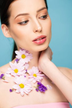 young woman with flowers on neck isolated on blue 