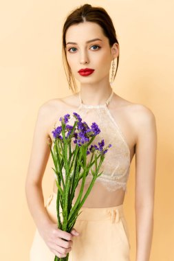 attractive woman holding limonium flowers isolated on beige 