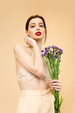 young pretty woman holding limonium flowers isolated on beige 