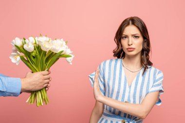 partial view of man presenting bouquet of white tulips to displeased girl showing no gesture isolated on pink clipart