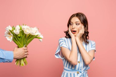 Kırpılmış beyaz lale buketi sunan adam manzarası Pembe üzerinde izole edilmiş genç bir kadına
