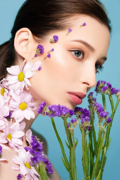 pretty woman near blossoming flowers isolated on blue 