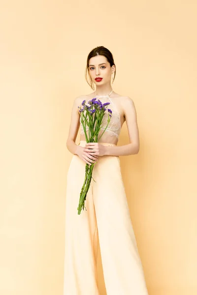 Attractive Woman Holding Purple Limonium Flowers Standing Isolated Beige — Stok fotoğraf