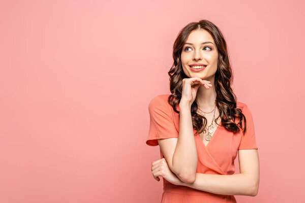 счастливая молодая женщина, держась за руку рядом с лицом, отводя взгляд на розовый
