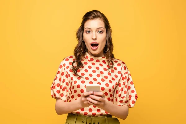 Scioccato Giovane Donna Guardando Fotocamera Tenendo Smartphone Isolato Giallo — Foto Stock