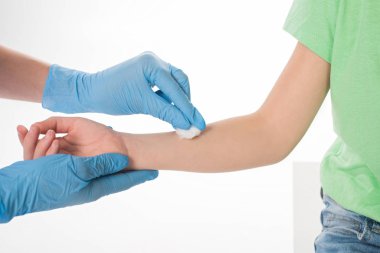 Lateks eldivenli çocuk doktorunun kırpılmış görüntüsü beyaz yünlü çocuğun elini ovuyor.
