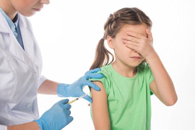 Pediyatrist, beyaz tenli, korkmuş çocuğa aşı enjekte ediyor.