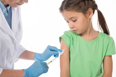 Aşı yapan bir pediyatrist. Beyazlar içinde izole edilmiş bir çocuğa aşı yapıyor.