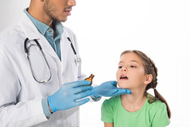 Steteskoplu bir çocuk doktoru, beyazlar içinde izole edilmiş çocuklara karışım veriyor.