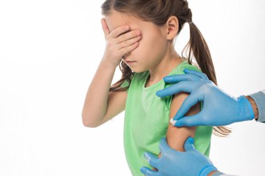 Beyaz tenli, korkmuş bir çocuğun omuzlarını ovalayan pamuklu çocuk doktorunun yan görüntüsü