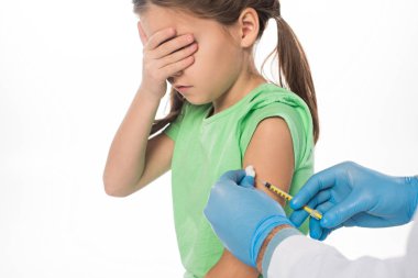 Beyaz tenli, korkmuş çocuğa aşı enjekte eden çocuk doktorunun yan görüntüsü