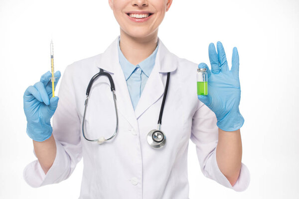 Cropped view of smiling doctor holding syringe and green vaccine isolated on white