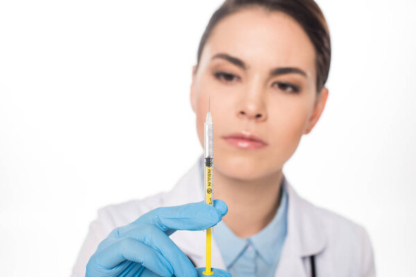 Selective focus of attractive doctor looking at syringe with vaccine isolated on white