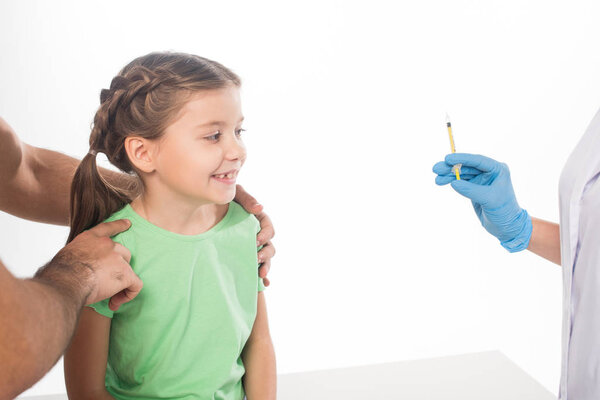 Father holding smiling kid near pediatrician with syringe isolated on white