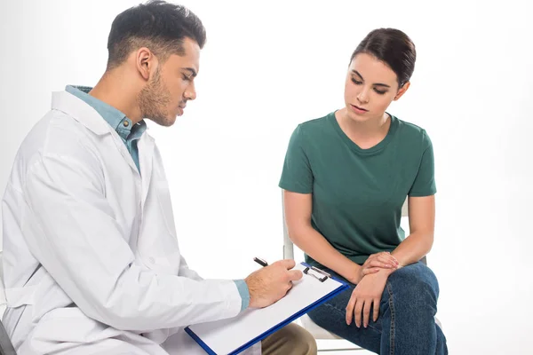 Guapo Doctor Escribiendo Portapapeles Cerca Paciente Femenina Aislado Blanco — Foto de Stock