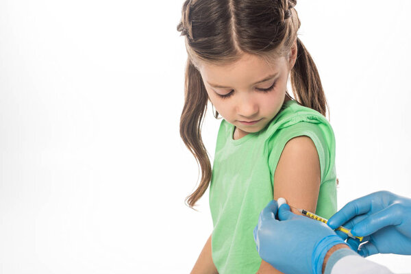 Side view of kid looking at pediatrician doing vaccine injection isolated on white