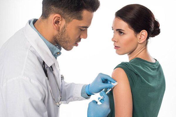 Female patient looking at doctor doing vaccine injection isolated on white