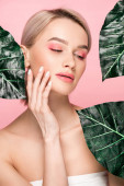 atraktivní dívka s růžovou make-up izolované na růžové se zelenými listy 