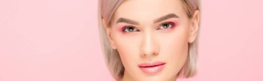 Pembe makyajlı çekici kızın panoramik çekimi, pembe üzerine izole edilmiş.