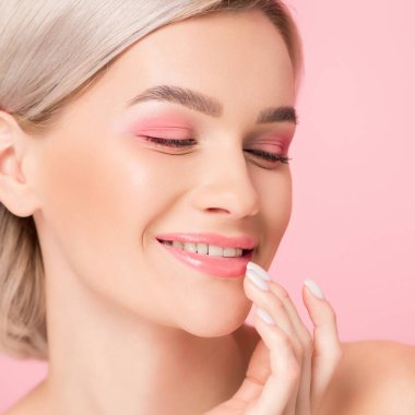 pembe makyajlı güzel bir kız dudaklarına dokunuyor, pembe renkte izole edilmiş.