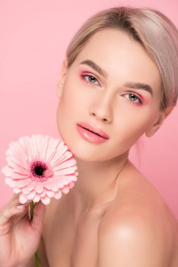 pembe makyajlı çıplak bir kadın çiçek tutuyor, pembe renkte izole edilmiş.