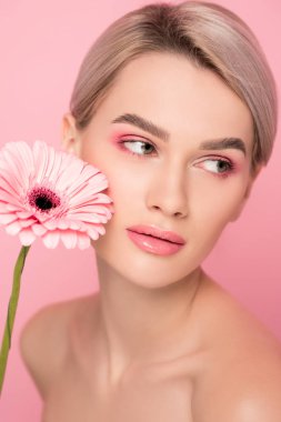 Pembe makyajlı çıplak bir kız ve pembe bir çiçek.