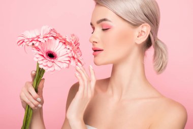 Pembe çiçeklere bakan, pembe tenli çekici bir kız.