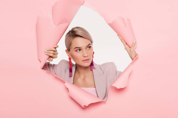 модная модель в модном костюме, позирующая в порванной бумаге, изолированная на белом
