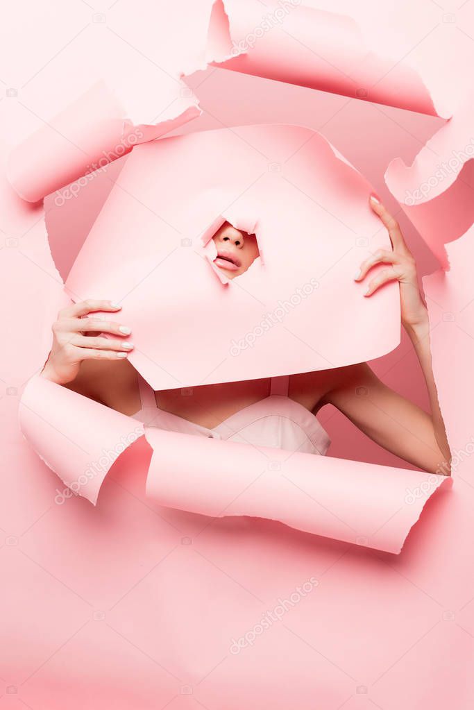 stylish model posing with pink torn paper, on pink