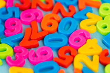 Selective focus of colorful plastic numbers on blue surface clipart