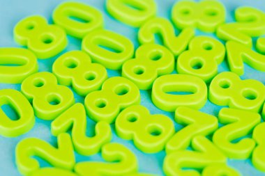 Mavi arkaplanda yeşil plastik sayıların seçici odak noktası