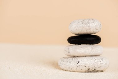 Close up view of stacked zen stones on sand isolated on beige  clipart