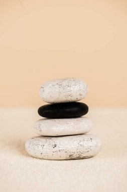 Close up view of natural zen stones on sand on beige background clipart