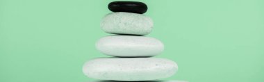 Panoramic shot of stacked zen stones isolated on green  clipart