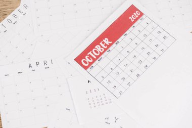 Top view of paper monthly calendars on wooden background clipart